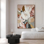A framed canvas print titled 'Harmony', featuring a floral composition with earthy tones, displayed in a room with a white sofa and a black side table.