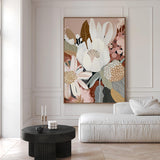 A framed canvas print titled 'Harmony', featuring a floral composition with earthy tones, displayed in a room with a white sofa and a black side table.