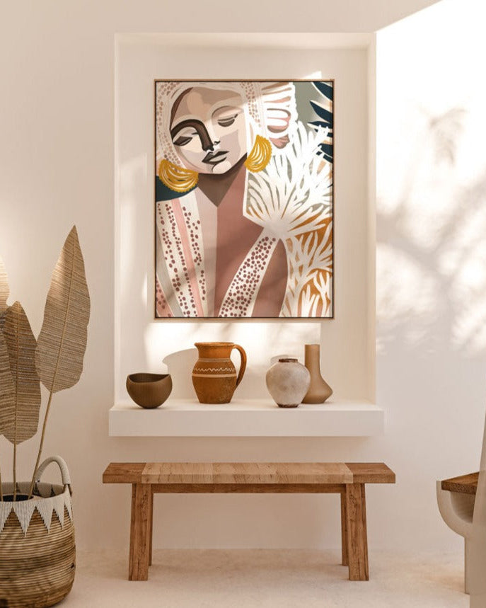 A framed canvas print titled 'Cala Luna', depicting an abstract image with flowing forms and soft, shadowed colors, displayed on a white wall above a bench with decorative pots and bottles.