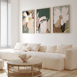 A set of three framed art prints featuring floral and bird motifs, displayed above a white sofa in a modern living room setting.