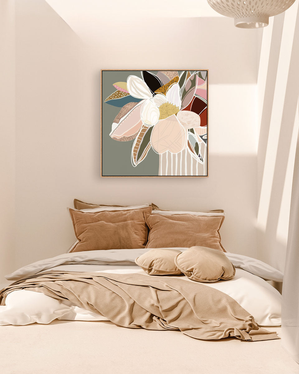 A framed canvas print with abstract florals in sage colors displayed above a bed with beige bedding and brown pillows.