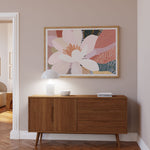 Wooden sideboard with a floral painting above it in a room with beige walls and wooden floor.
