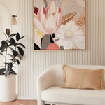 A framed canvas print featuring a serene spring motif, with a pastel color scheme, hanging on a wall above a white sofa, next to a wooden side table hosting a decorative vase.