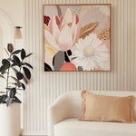 A framed canvas print featuring abstract floral art, displayed above a white sofa with gold cushions, in a room with striped wallpaper.