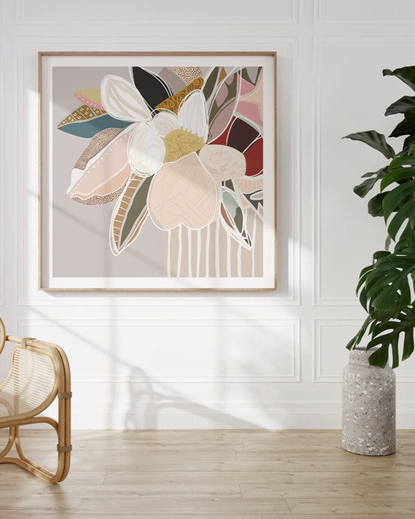 A framed print featuring abstract floral elements in neutral colors displayed on a wall above a chair and a potted plant.