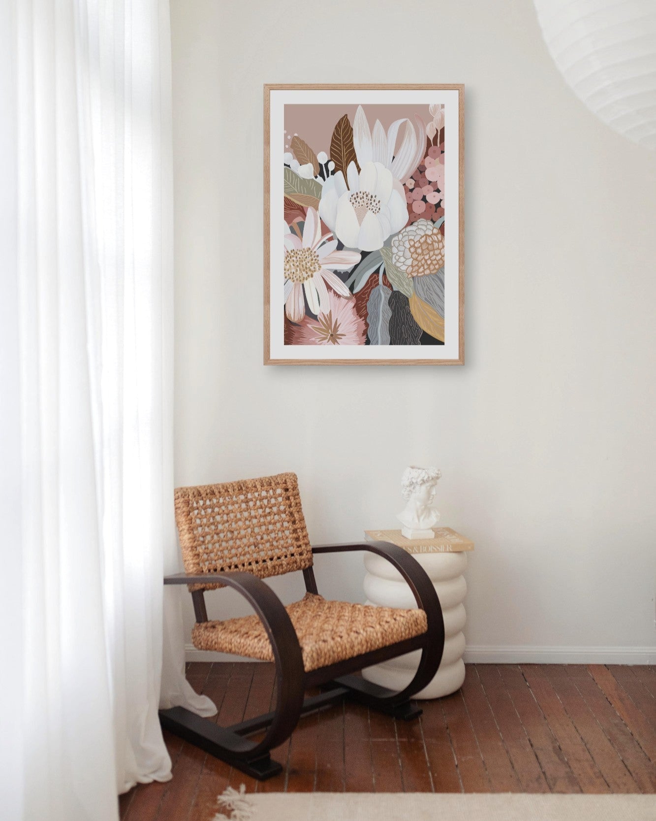 A framed print featuring a floral arrangement displayed above a vintage-style chair in a room with a light interior.
