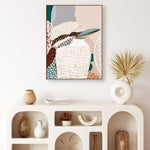 A framed canvas print titled 'Kookaburra in Pink No.2' displayed on a white wall, featuring an abstract depiction of a kookaburra with soft pink and beige tones.