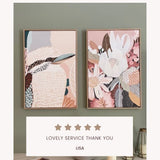 A framed canvas print titled 'Kookaburra in Pink No.2' displayed on a white wall, featuring an abstract depiction of a kookaburra with soft pink and beige tones.