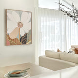 A framed canvas print of an abstract floral artwork featuring a magnolia flower, displayed on a wall above a modern sofa in a well-lit living room.