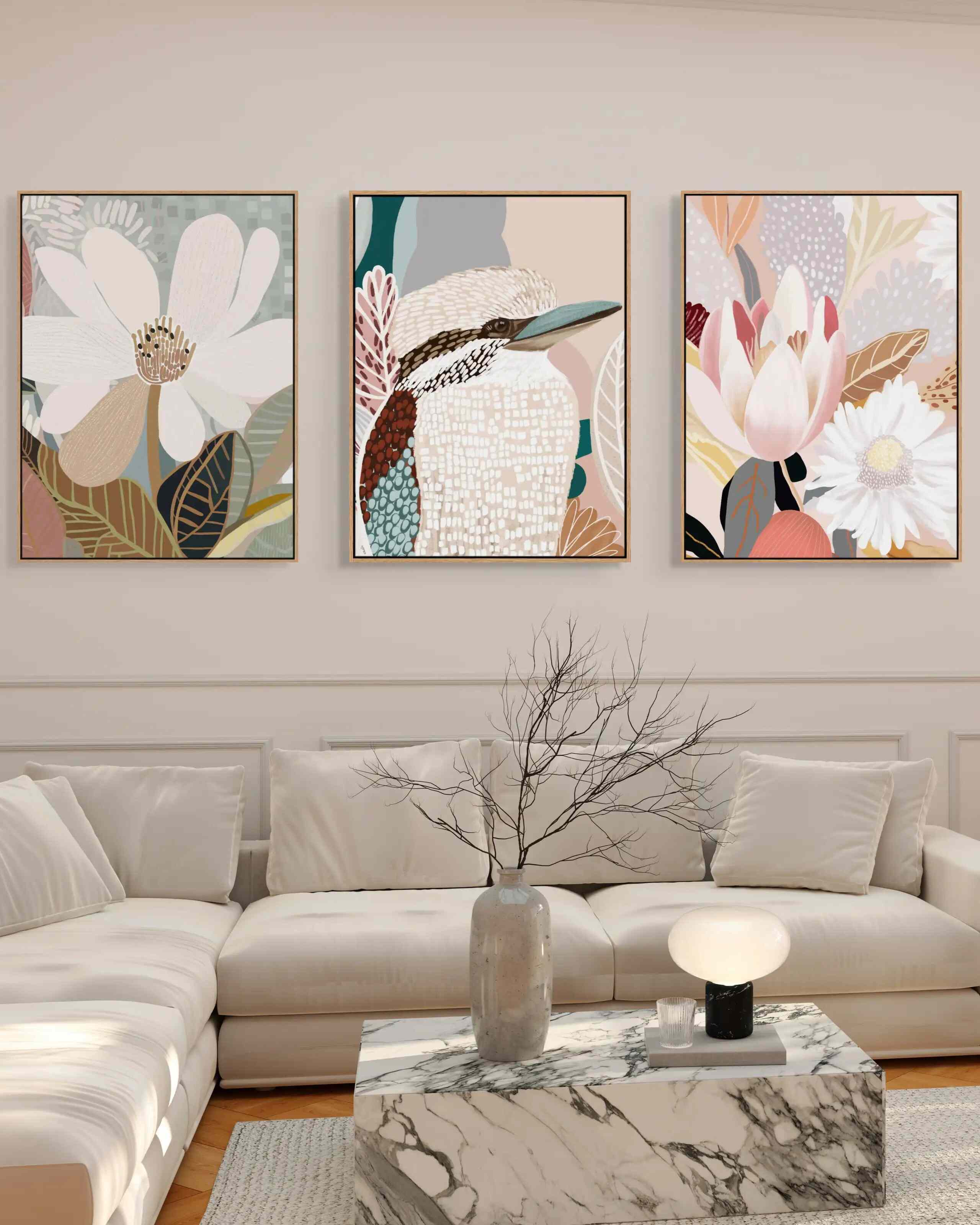 A set of three framed canvas prints with floral artwork displayed above a modern sofa in a living room setting.
