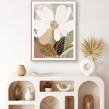 A framed print of an abstract floral artwork featuring a magnolia flower on a white wall, with decorative items arranged on a white shelf below.