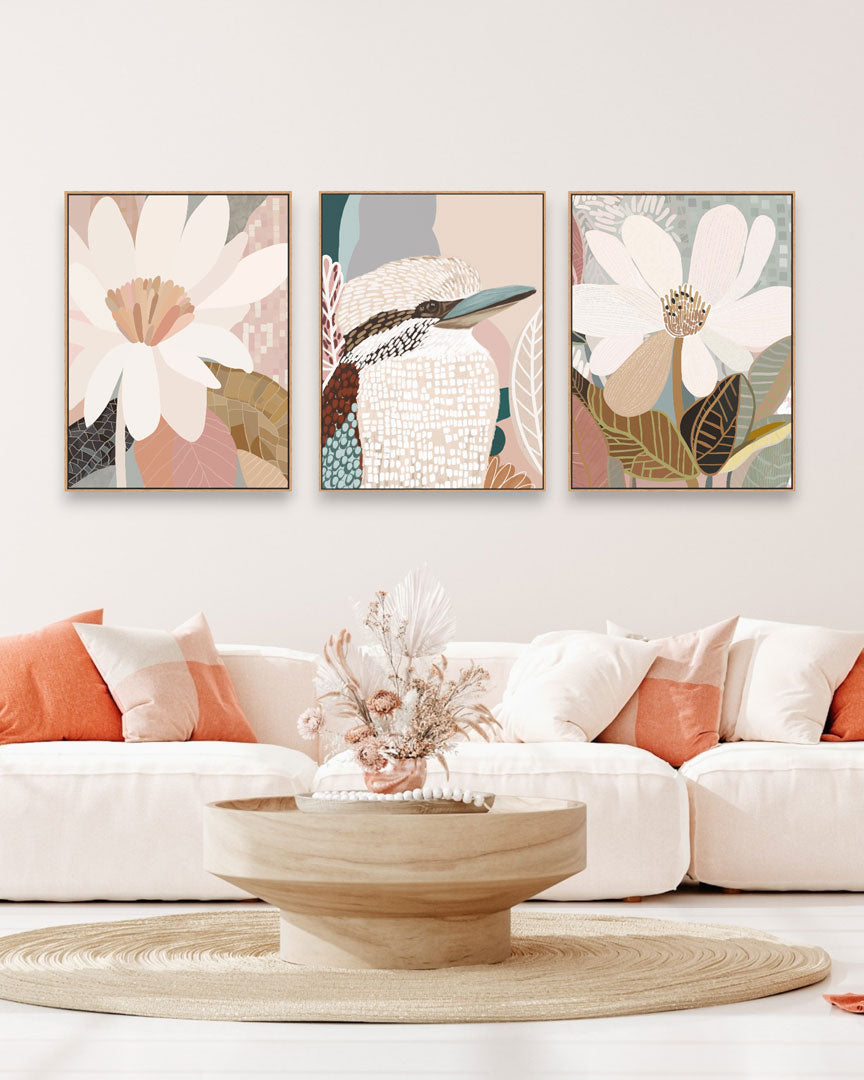 A set of three framed canvas prints featuring floral and animal artwork displayed above a white sofa in a living room setting.