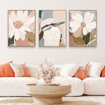 A set of three framed canvas prints featuring floral and animal artwork displayed above a white sofa in a living room setting.
