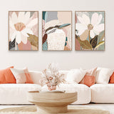A set of three framed canvas prints featuring floral and animal artwork displayed above a white sofa in a living room setting.