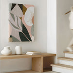A framed canvas print titled 'Odeletta', featuring abstract geometric patterns in pink and navy colors, displayed above a wooden bench in a minimalist interior setting.