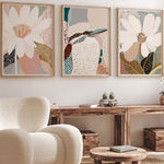 A set of three framed art prints featuring abstract floral designs, displayed in a living room setting with a modern armchair and wooden furniture.