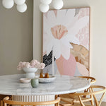 Dining room with marble table, floral artwork, and decorative items.