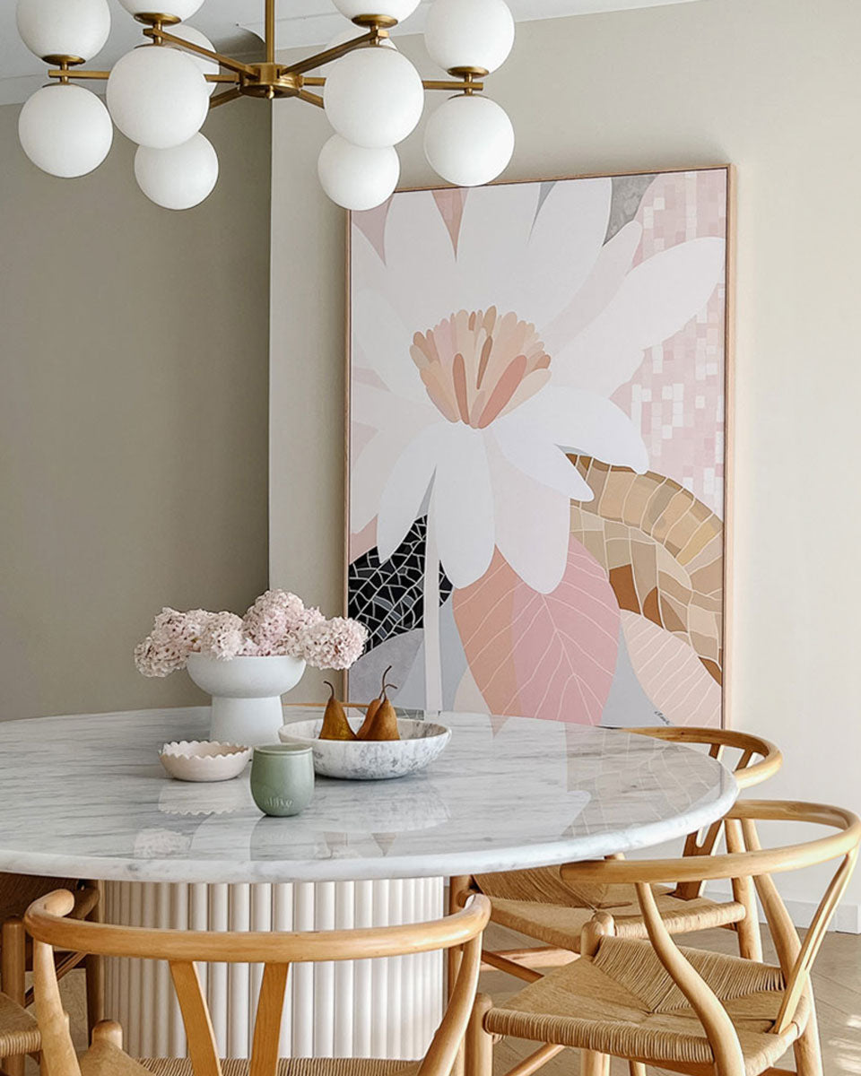 Dining room with marble table, floral artwork, and decorative items.