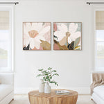A pair of framed canvas prints titled 'Reverie No.2' and 'Magnolia' displayed in a living room setting with a natural oak frame and a classic black moulding, respectively.