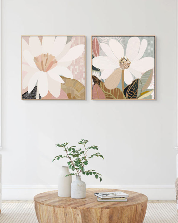 Two framed canvas prints with floral artwork hanging on a wall above a wooden table.