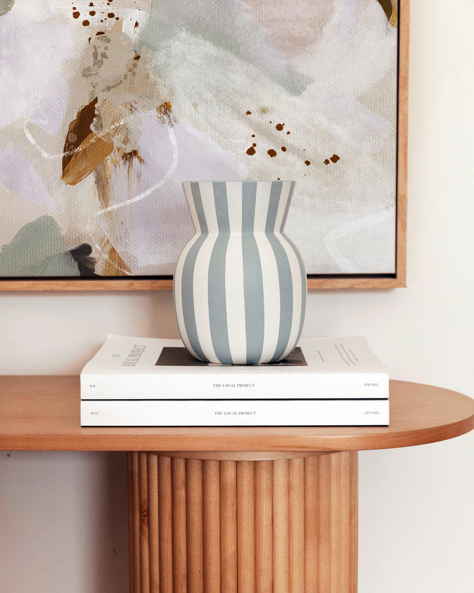 Striped vase on books with abstract art in the background