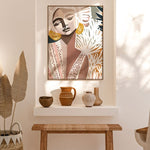 A framed canvas print titled 'Cala Luna', depicting an abstract image with flowing forms and soft, shadowed colors, displayed on a white wall above a bench with decorative pots and bottles.