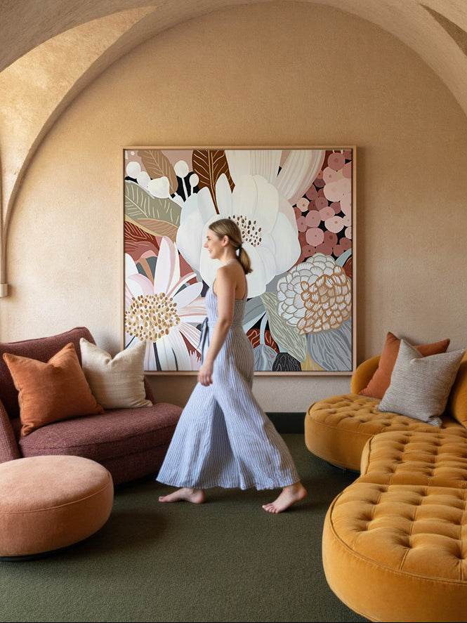 Woman standing in a stylish living room with a large abstract painting on the wall.