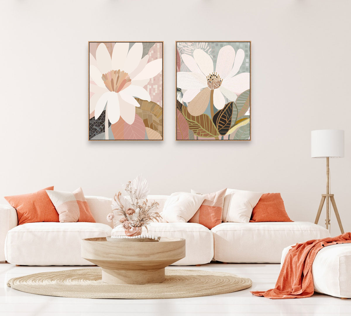 Two framed canvas prints featuring floral artwork, hanging on a wall above a white sofa, with one print slightly to the left and the other to the right. The room is styled with neutral tones and has a modern aesthetic.