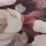 A close-up of a floral fabric print featuring large pale pink blossoms with brown centers and darker plum-purple leaves on a dark background.