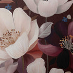 A close-up of a floral painting or print featuring large pale pink blossoms, a dark burgundy flower with yellow stamens, and muted green and blue leaves on a dark brown background.