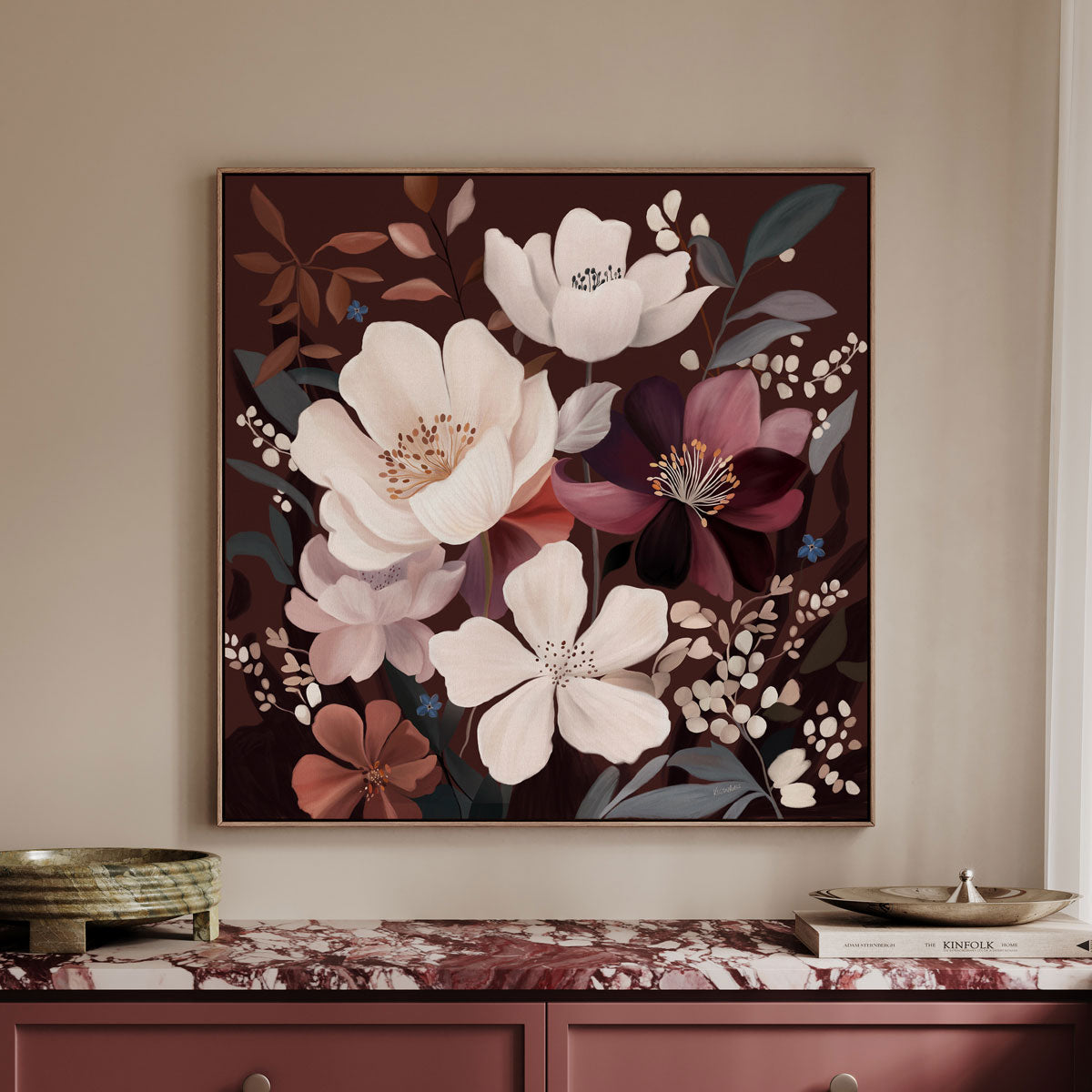 A framed floral wall art piece hangs above a console table. The artwork features large white and burgundy flowers with muted green and brown leaves on a dark brown background.