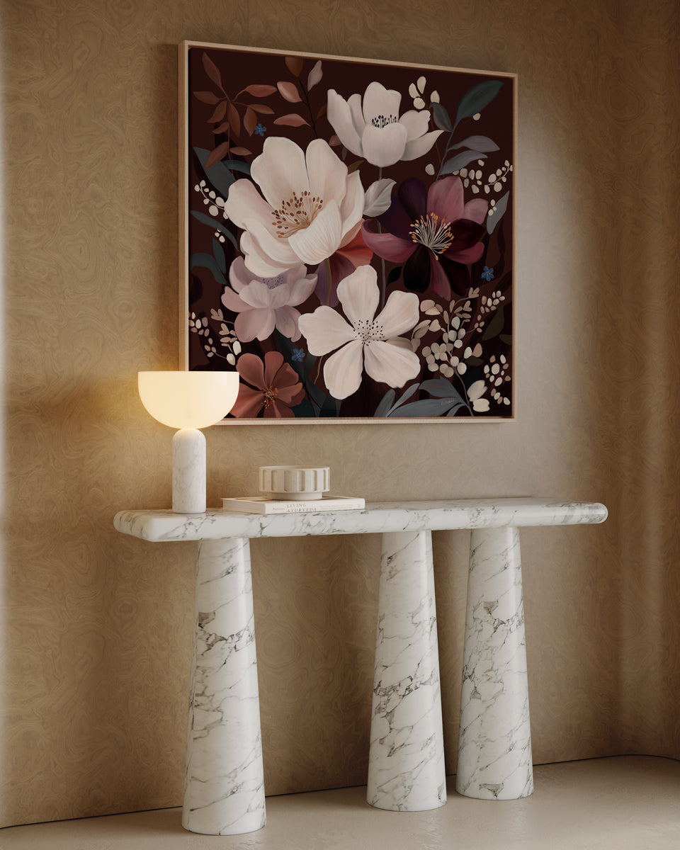 Marble console table with decorative items against a beige wall with floral artwork.