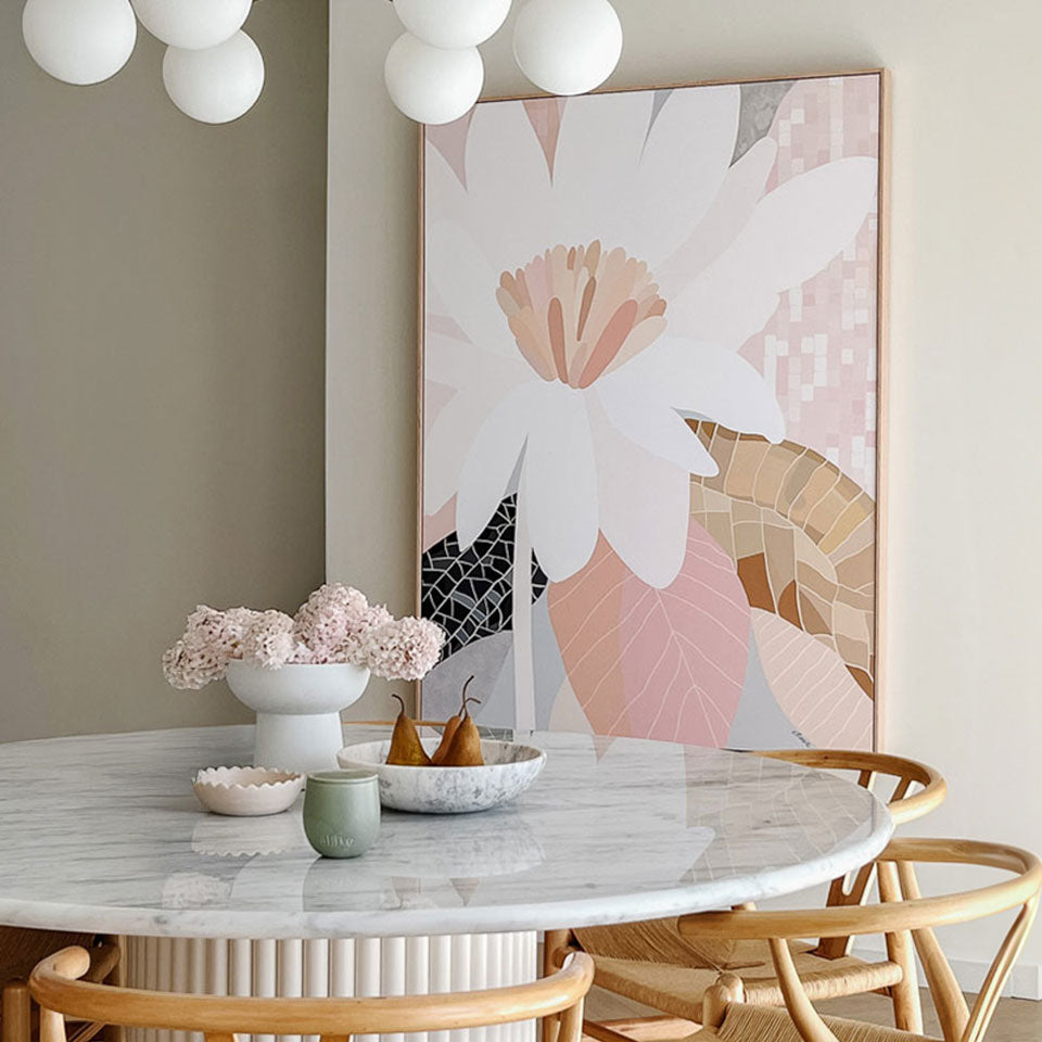 Dining room with marble table, floral artwork, and decorative items.