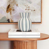 Striped vase on books with abstract art in the background